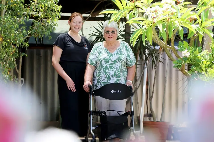 young lady supporting older lady with walking frame